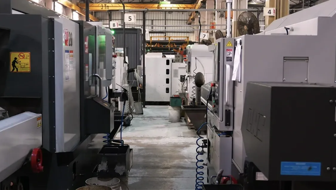 Pasillo de la planta de HSF entre dos filas de tornos CNC, con el puente grúa al fondo